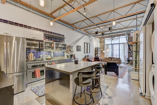 111 N Main St Unit 209, Royal Oak, MI 48067 - kitchen featuring stainless steel appliances, stacked washer / drying machine, a center island, decorative light fixtures, and white cabinetry