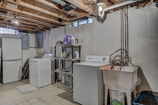 laundry room featuring washing machine and clothes dryer, electric panel, tile patterned floors, and a textured wall