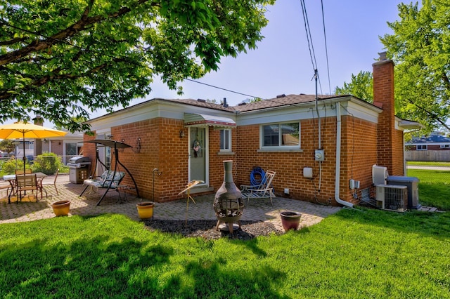 back of house with a patio, brick siding, a yard, and a chimney