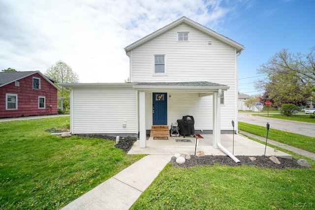 view of front of property with entry steps, a front lawn, and a patio