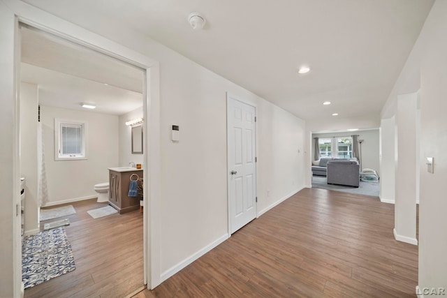 hallway with wood finished floors, baseboards, and recessed lighting