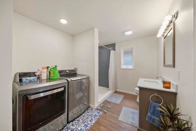 full bath featuring washer and clothes dryer, toilet, wood finished floors, curtained shower, and baseboards