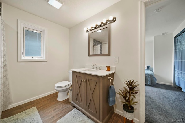 bathroom featuring baseboards, toilet, vanity, and wood finished floors