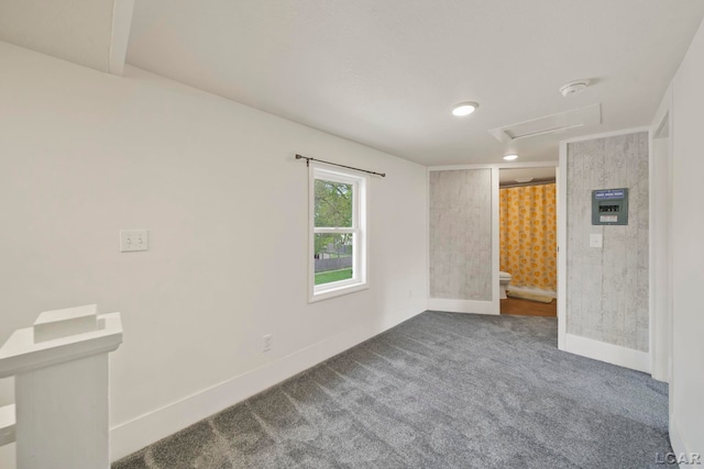 empty room featuring dark carpet, baseboards, and attic access