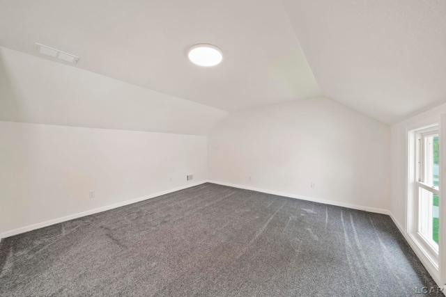 bonus room with lofted ceiling, dark colored carpet, and baseboards
