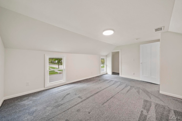 carpeted spare room with vaulted ceiling, baseboards, and healthy amount of natural light