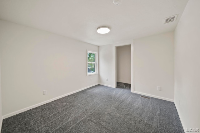 unfurnished room with baseboards and dark colored carpet