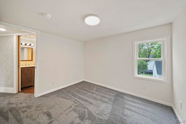 spare room featuring carpet flooring, baseboards, a sink, and a smoke detector