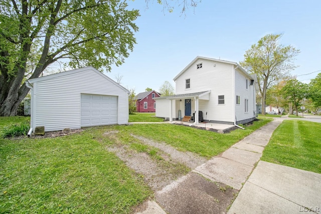 back of house featuring driveway, an outbuilding, a garage, and a lawn