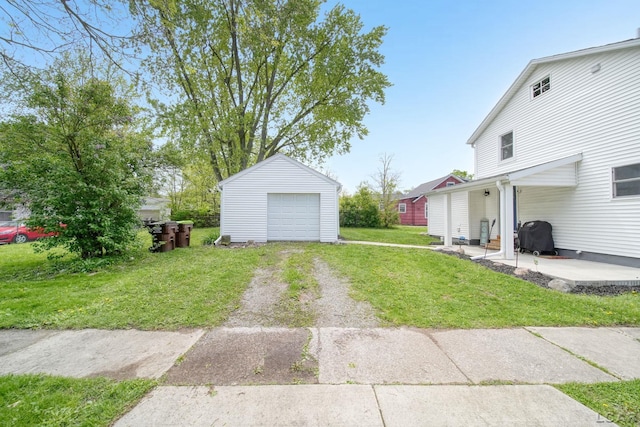 view of grassy yard with dirt driveway, an outdoor structure, a garage, and a patio