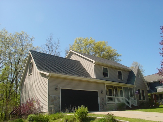 10832 Eagle Cove Dr, South Lyon, MI 48178 - view of front of house with covered porch, an attached garage, stone siding, and concrete driveway