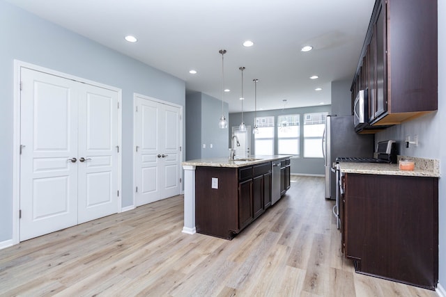 951 Barclay Cir Unit 48, Rochester Hills, MI 48307 - kitchen featuring dark brown cabinetry, stainless steel appliances, a center island with sink, light wood-style floors, and baseboards