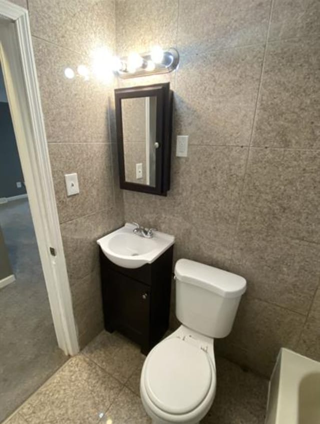 1778 Reo Ave, Lincoln Park, MI 48146 - bathroom featuring a bathtub, toilet, vanity, tile walls, and tile patterned flooring