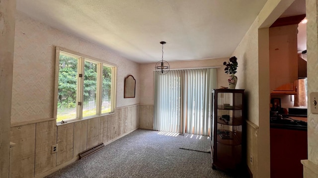 1821 W Hansen Rd, Scottville, MI 49454 - unfurnished dining area featuring a wainscoted wall, carpet, and a chandelier