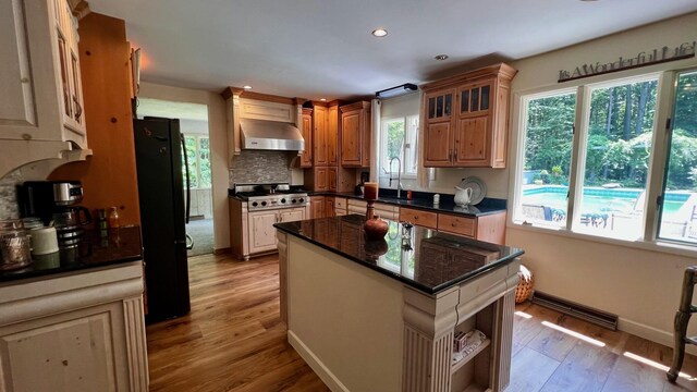 1821 W Hansen Rd, Scottville, MI 49454 - kitchen featuring freestanding refrigerator, light wood-style flooring, wall chimney range hood, a sink, and open shelves