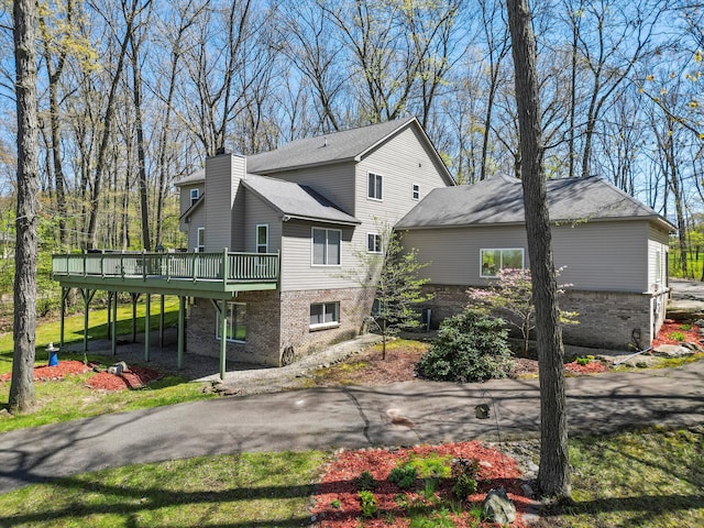 7111 Tucker Rd, Holly, MI 48442 - view of home's exterior with a wooden deck, a chimney, and brick siding