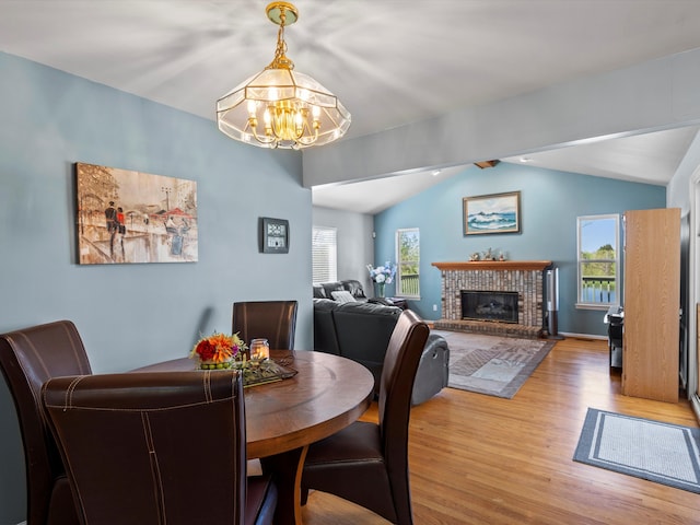 7111 Tucker Rd, Holly, MI 48442 - dining space featuring a chandelier, light wood-type flooring, lofted ceiling, and a brick fireplace