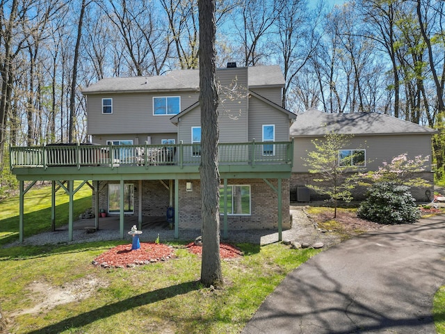 7111 Tucker Rd, Holly, MI 48442 - rear view of house featuring a deck, brick siding, a lawn, and a carport