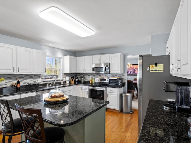 7111 Tucker Rd, Holly, MI 48442 - kitchen with stainless steel appliances, a sink, a breakfast bar area, backsplash, and dark stone countertops