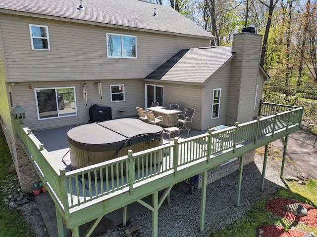 7111 Tucker Rd, Holly, MI 48442 - back of house featuring a hot tub, a deck, a chimney, and roof with shingles