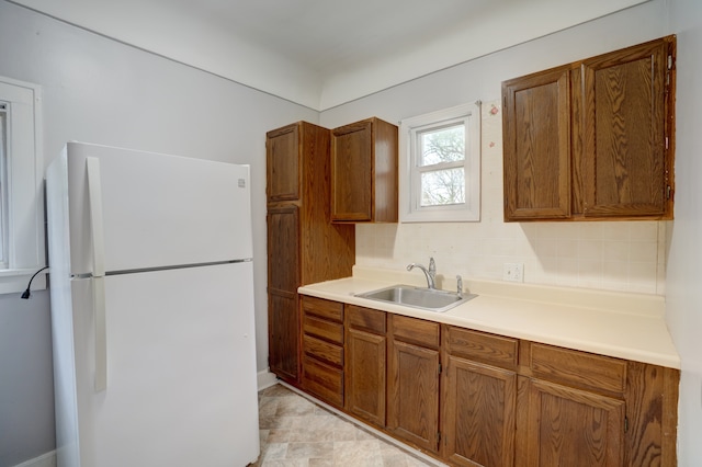 715 N St, Mount Morris, MI 48458 - kitchen featuring freestanding refrigerator, a sink, brown cabinetry, tasteful backsplash, and light countertops