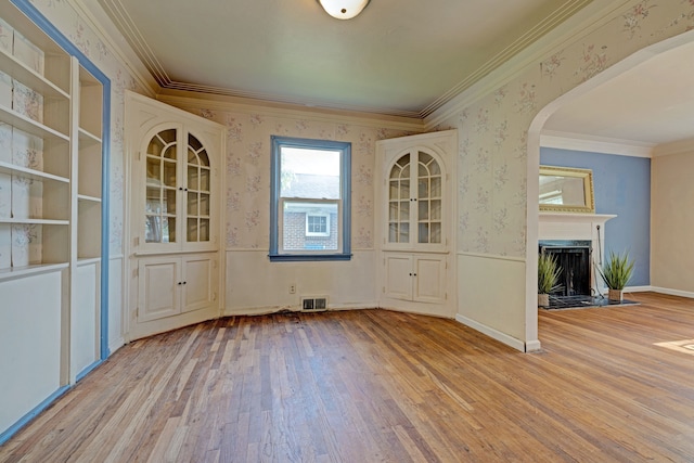 419 S State Rd, Davison, MI 48423 - unfurnished dining area featuring wallpapered walls, wood finished floors, ornamental molding, a fireplace, and arched walkways