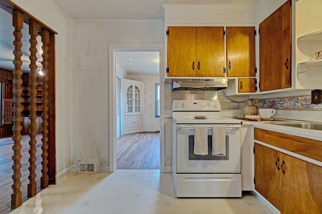 419 S State Rd, Davison, MI 48423 - kitchen featuring white range with electric cooktop, under cabinet range hood, light countertops, brown cabinetry, and crown molding