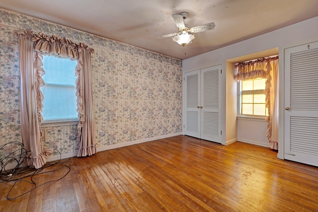 419 S State Rd, Davison, MI 48423 - unfurnished bedroom featuring light wood-type flooring, multiple closets, wallpapered walls, baseboards, and ceiling fan
