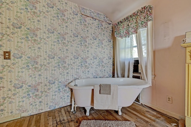 419 S State Rd, Davison, MI 48423 - bathroom featuring wood-type flooring, a freestanding tub, vaulted ceiling, and baseboards