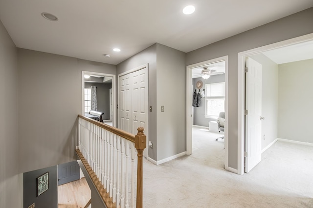 corridor featuring an upstairs landing, baseboards, recessed lighting, and light carpet