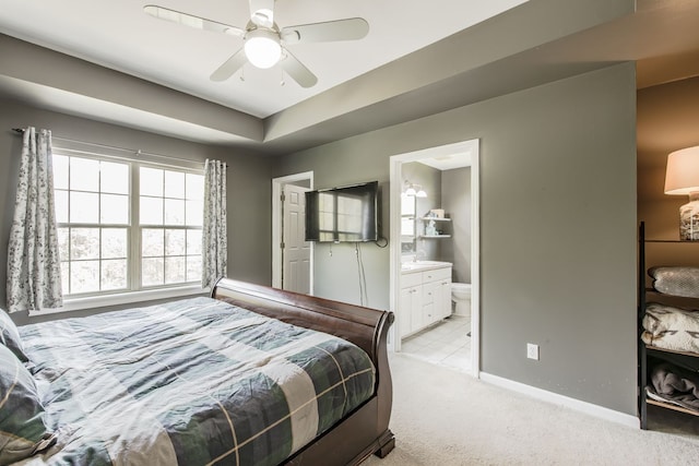 bedroom with light carpet, baseboards, ensuite bath, and ceiling fan