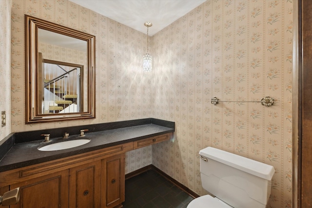 half bath with toilet, vanity, tile patterned flooring, and baseboards