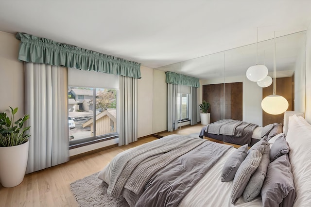 bedroom featuring light wood finished floors and a baseboard heating unit