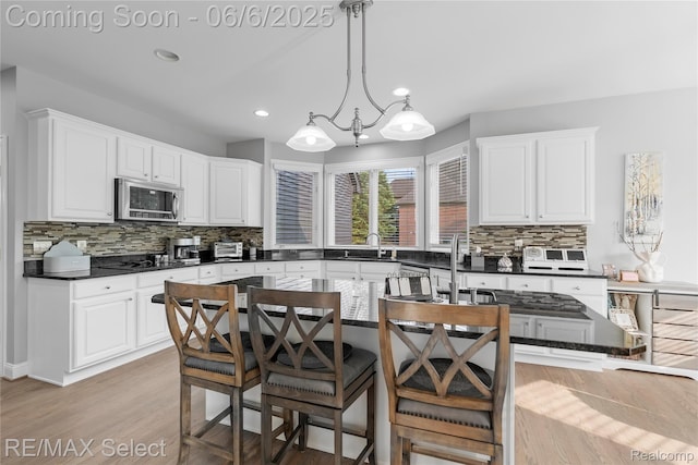 8320 Misty Mdws, Grand Blanc, MI 48439 - kitchen featuring stainless steel microwave, dark countertops, decorative backsplash, white cabinetry, and recessed lighting