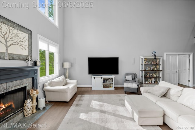 8320 Misty Mdws, Grand Blanc, MI 48439 - living room featuring a high ceiling, wood finished floors, a tile fireplace, and baseboards