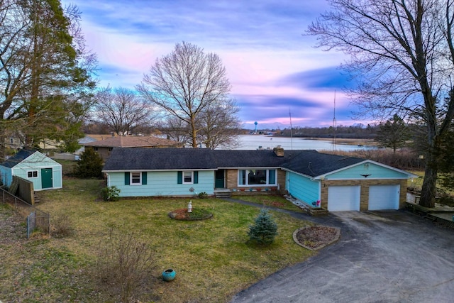 1090 Sunset Dr, Holly, MI 48442 - ranch-style home with asphalt driveway, an attached garage, a water view, and a chimney