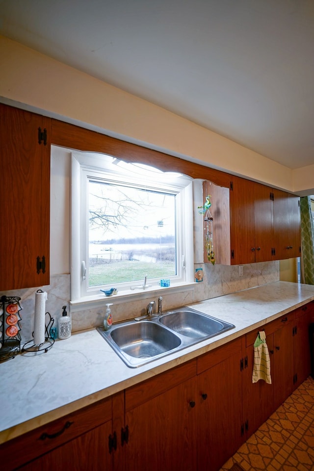 1090 Sunset Dr, Holly, MI 48442 - kitchen with light countertops, a sink, brown cabinetry, and backsplash