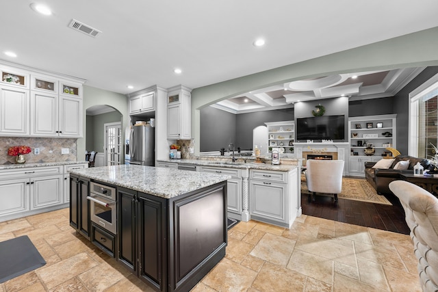 25031 Newton St, Dearborn, MI 48124 - kitchen with arched walkways, stainless steel fridge with ice dispenser, open floor plan, white cabinets, and crown molding