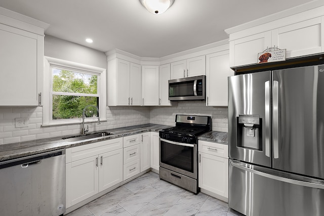 1090 S Williams Lake Rd, White Lake, MI 48386 - kitchen with appliances with stainless steel finishes, a sink, light marble finish flooring, white cabinetry, and tasteful backsplash