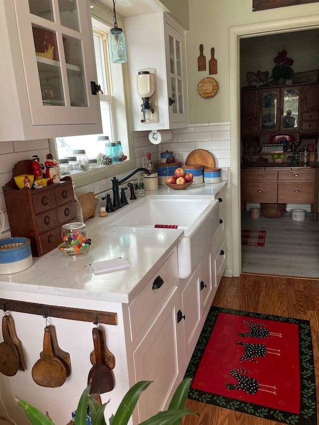 kitchen featuring white cabinets, glass insert cabinets, decorative light fixtures, and a sink