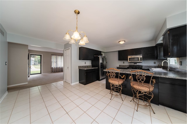 3142 Buss Dr, Commerce Twp, MI 48390 - kitchen with stainless steel appliances, dark cabinetry, a sink, and a chandelier