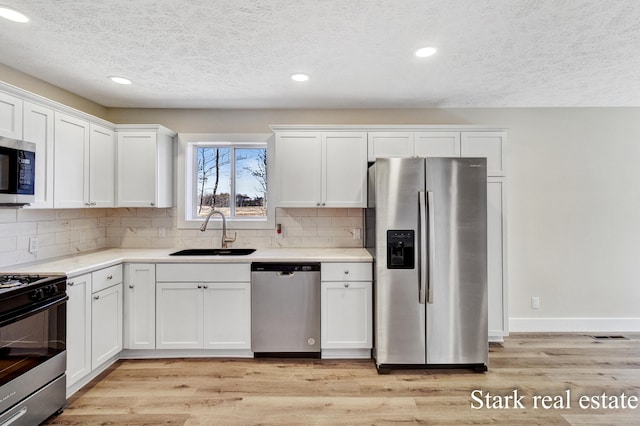 3339 N Weber Rd, Muskegon, MI 49445 - kitchen with stainless steel appliances, a sink, a textured ceiling, backsplash, and white cabinetry