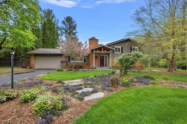 split level home featuring a chimney, a garage, brick siding, and driveway