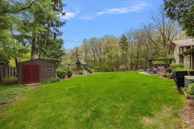 view of yard featuring a shed, a playground, a fire pit, an outdoor structure, and a patio area