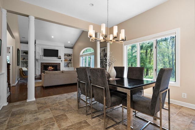 1303 Towsley Ln, Ann Arbor, MI 48105 - dining room featuring a chandelier, stone tile flooring, a brick fireplace, lofted ceiling, and baseboards