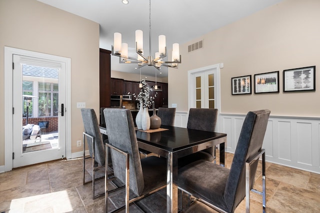 1303 Towsley Ln, Ann Arbor, MI 48105 - dining space featuring a chandelier, light stone finish floors, wainscoting, and a high ceiling