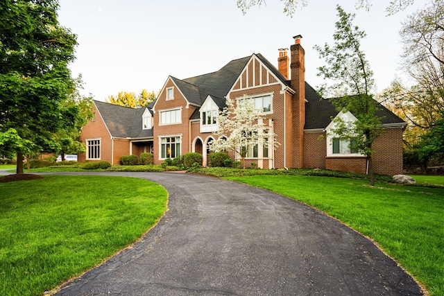 1303 Towsley Ln, Ann Arbor, MI 48105 - tudor home featuring brick siding, a front yard, a chimney, and curved driveway