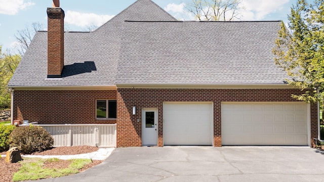 1303 Towsley Ln, Ann Arbor, MI 48105 - view of front of property with asphalt driveway, a shingled roof, a chimney, an attached garage, and brick siding
