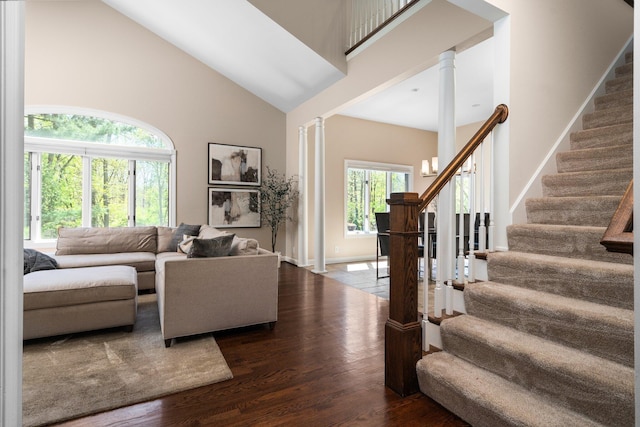 1303 Towsley Ln, Ann Arbor, MI 48105 - living room with high vaulted ceiling, decorative columns, dark wood finished floors, stairs, and a chandelier