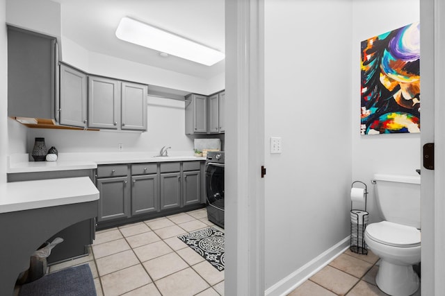 1303 Towsley Ln, Ann Arbor, MI 48105 - kitchen with gray cabinetry, light tile patterned floors, washer / dryer, light countertops, and a sink